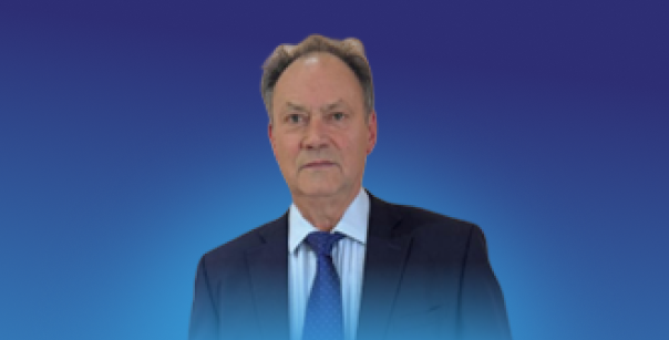 A person in formal business attire standing against a blue gradient background.