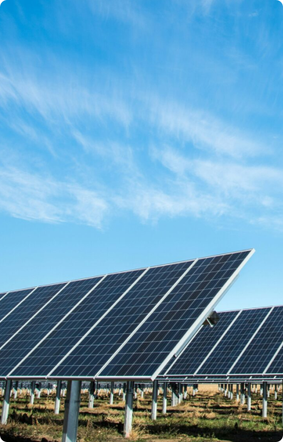 Rows of solar panels installed outdoors on metal supports under a bright blue sky with scattered clouds.