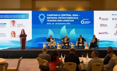 A conference panel on stage with several speakers seated in front of large display screens showing event information for Caspian and Central Asia.