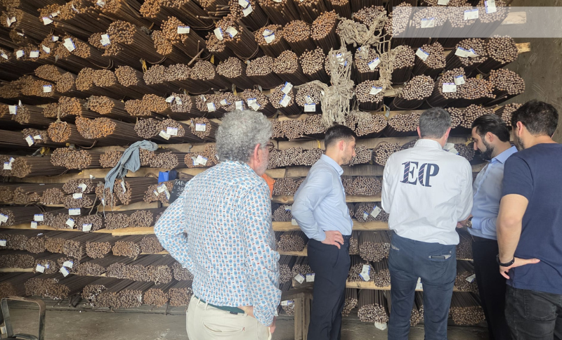 Group of individuals examining stacked metal rods inside an industrial storage area during Alkagesta’s West Africa site visit.