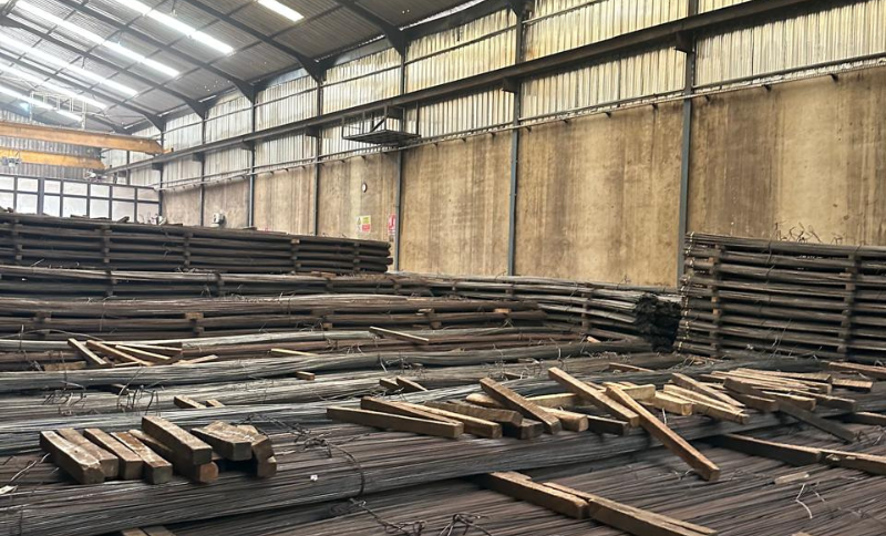 stacked steel bars and metal beams stored inside industrial warehouse facility