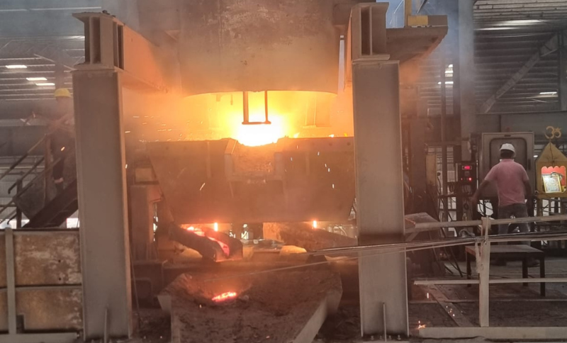 industrial metal processing furnace operation in West Africa facility with molten material and worker