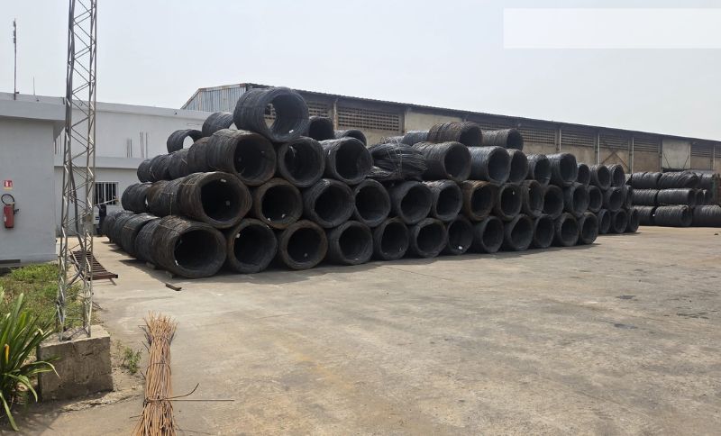 Stacks of large industrial steel wire coils stored outdoors at a manufacturing facility visited by Alkagesta.