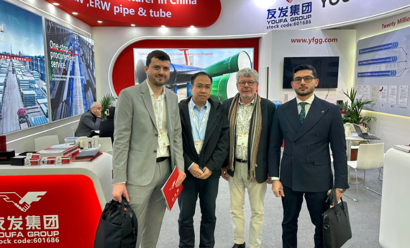 Participants standing at an industrial exhibition booth during Wire & Tube Düsseldorf, with branded displays for steel pipes, tubes, and manufacturing solutions visible in the background.