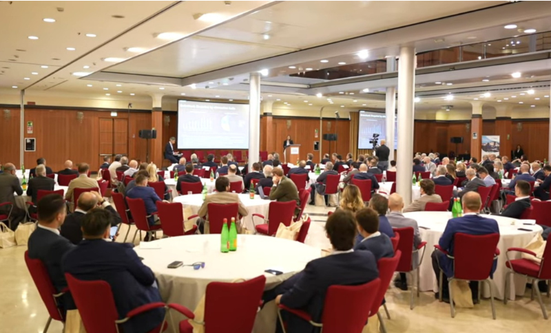 Conference session at Italian Ferry Summit 2026 in Naples with participants seated at round tables facing stage presentation