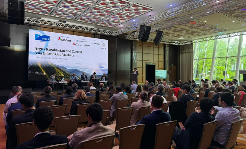Attendees sit facing a stage with panellists at the Argus Kazakhstan and Central Asia Oil and Gas Markets conference in a large, modern room with floor-to-ceiling windows and a presentation screen.