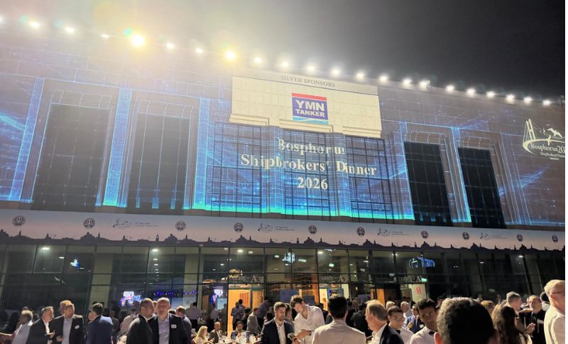 A large crowd gathers outside a brightly lit building with Bosphorus Shipbrokers’ Dinner 2026 projected on its facade, along with a sponsor logo, during a night event.