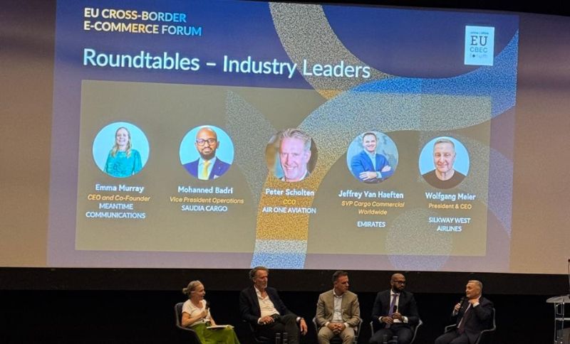 Five panellists sit on stage under a screen displaying their names and titles at the EU Cross-Border E-Commerce Forum, participating in a roundtable discussion for industry leaders.