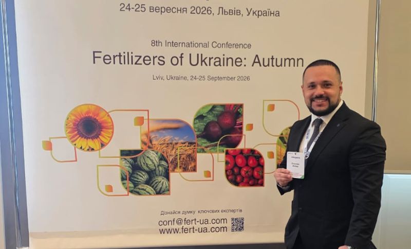 A man in a suit stands smiling beside a conference banner reading Fertilisers of Ukraine: Autumn, Lviv, Ukraine, 24-25 September 2026, with images of sunflowers, watermelons, apples, and tomatoes.