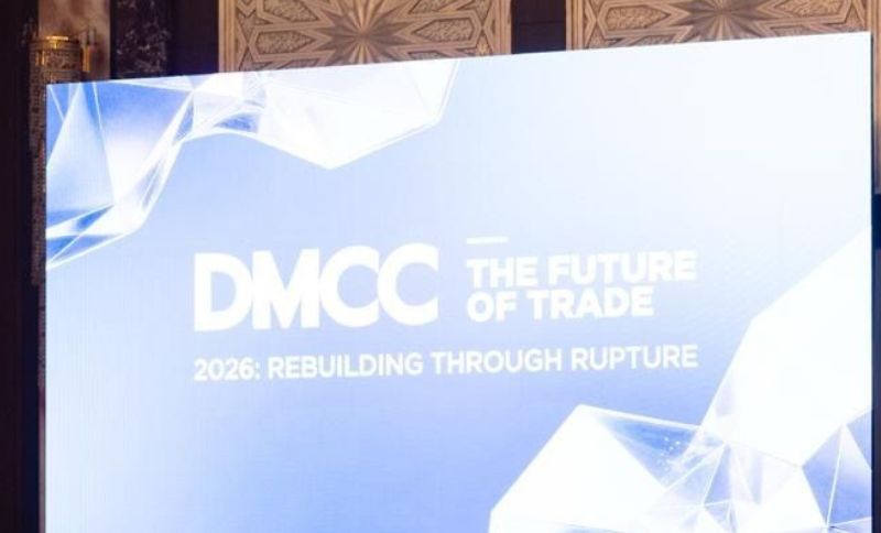 A large screen displays DMCC THE FUTURE OF TRADE 2026: REBUILDING THROUGH RUPTURE with a geometric design in a modern conference setting.