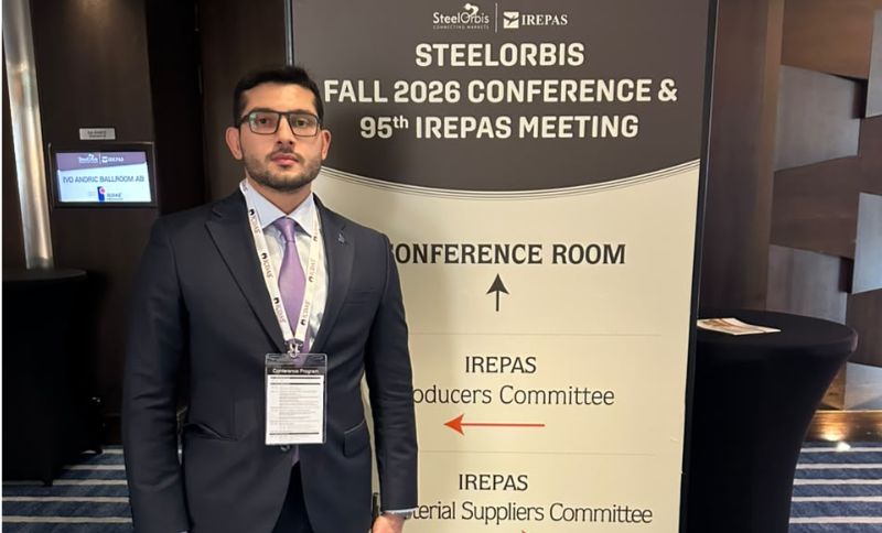 A man in a suit wearing a conference lanyard stands in front of a SteelOrbis and IREPAS autumn 2026 conference sign.