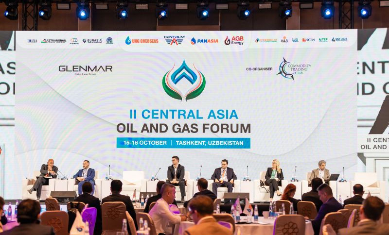 A panel of speakers seated on a stage at the II Central Asia Oil and Gas Forum in Tashkent, with event branding and sponsor logos displayed on a large screen behind them.