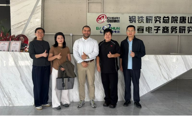 Five people stand in a queue giving a thumbs-up gesture in front of a company reception desk with CISRI and Baichun signage.