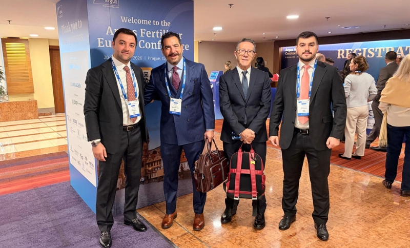 Four men in suits standing together at the Argus Fertiliser Europe Conference registration area.