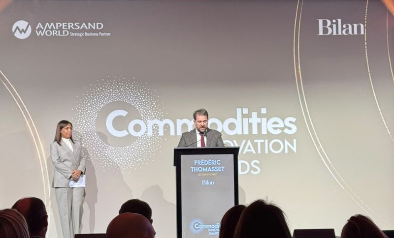 A man stands at a lectern giving a presentation on stage at the Commodities Innovation Awards, with a woman standing to his left.