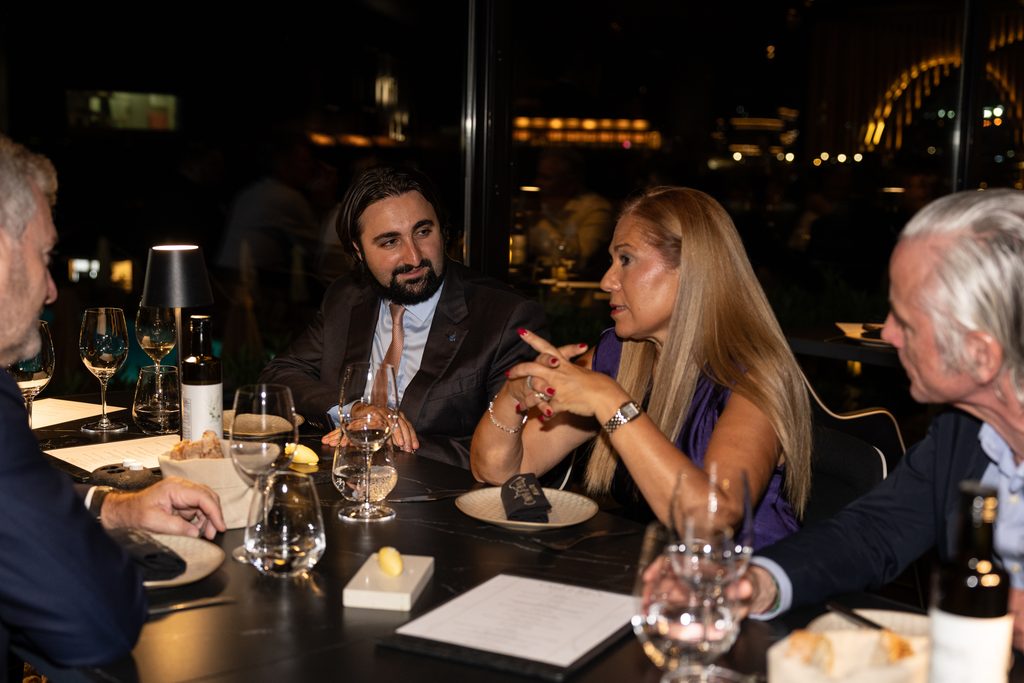 Four people seated around a table at a dimly lit restaurant during an evening event.